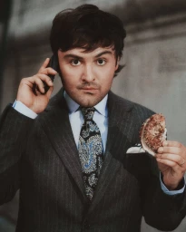 Man in a pinstripe suit holding a phone to his ear and a bagel in his hand for J. Crew