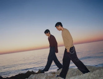 Two men walking along a rocky shoreline by the ocean at dusk for the H&M Diwali Collection 2026 campaign.
