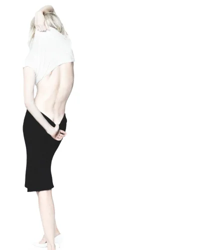 Dree Hemingway removing a white top wearing a black skirt against a seamless white background
