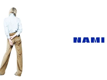 Dree Hemingway facing away wearing a light blue button-down shirt and brown trousers against white background with Nami logo
