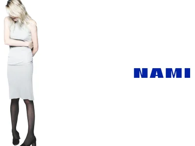 Model Dree Hemingway in a grey dress and black tights standing against a white seamless background with the Nami logo