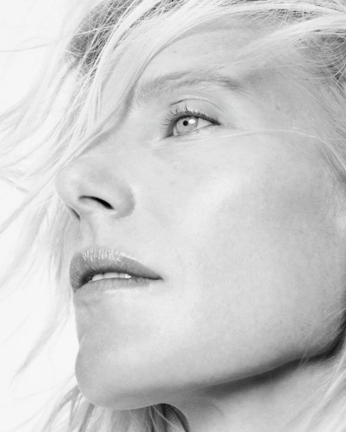 Close-up profile portrait of Dree Hemingway with flowing blonde hair against a bright white background
