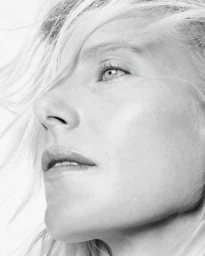 Close-up profile portrait of Dree Hemingway with flowing blonde hair against a bright white background