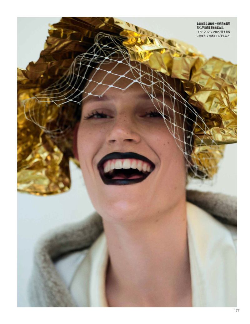 Model laughing with dark black lipstick wearing a gold foil hat and white netting veil for Vogue China editorial