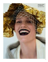 Model laughing with dark black lipstick wearing a gold foil hat and white netting veil for Vogue China editorial