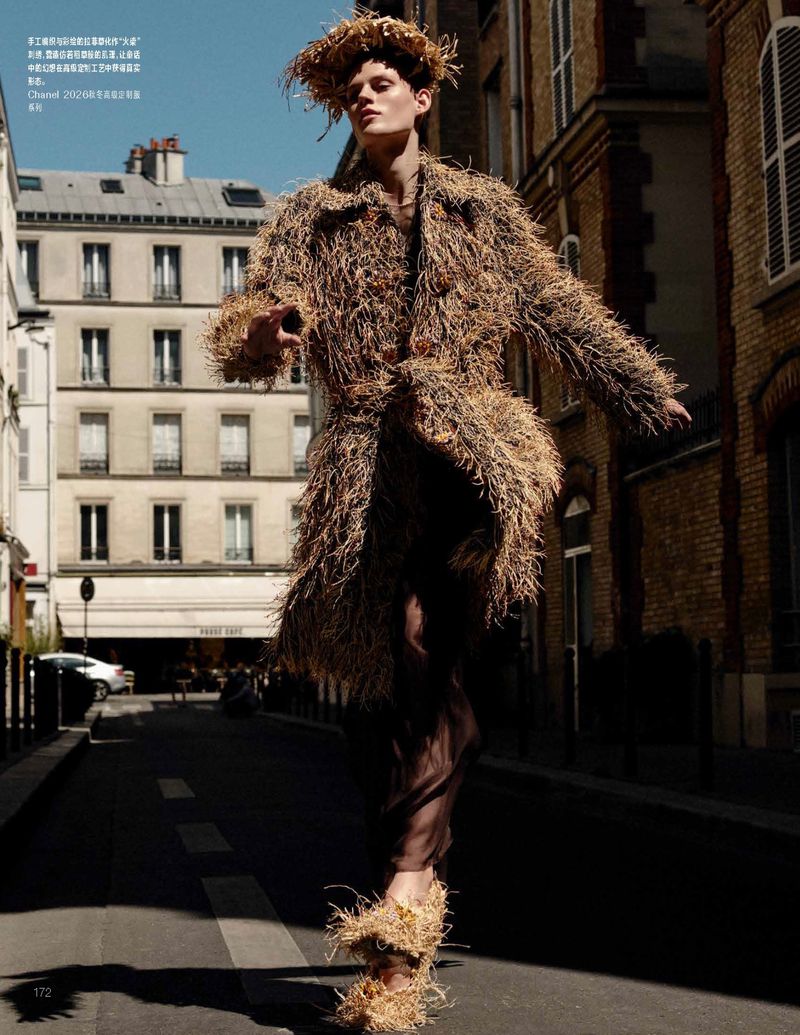 Model Bodine Van Galen wearing a straw-textured coat and headpiece walking down a Parisian street for Vogue China.