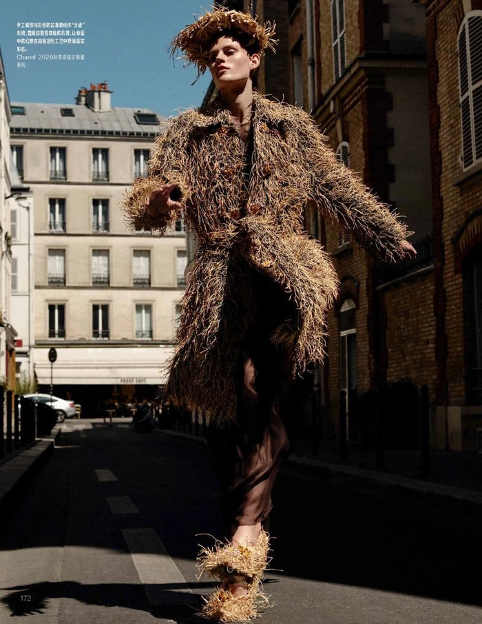 Model Bodine Van Galen wearing a straw-textured coat and headpiece walking down a Parisian street for Vogue China.