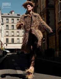 Model Bodine Van Galen wearing a straw-textured coat and headpiece walking down a Parisian street for Vogue China.