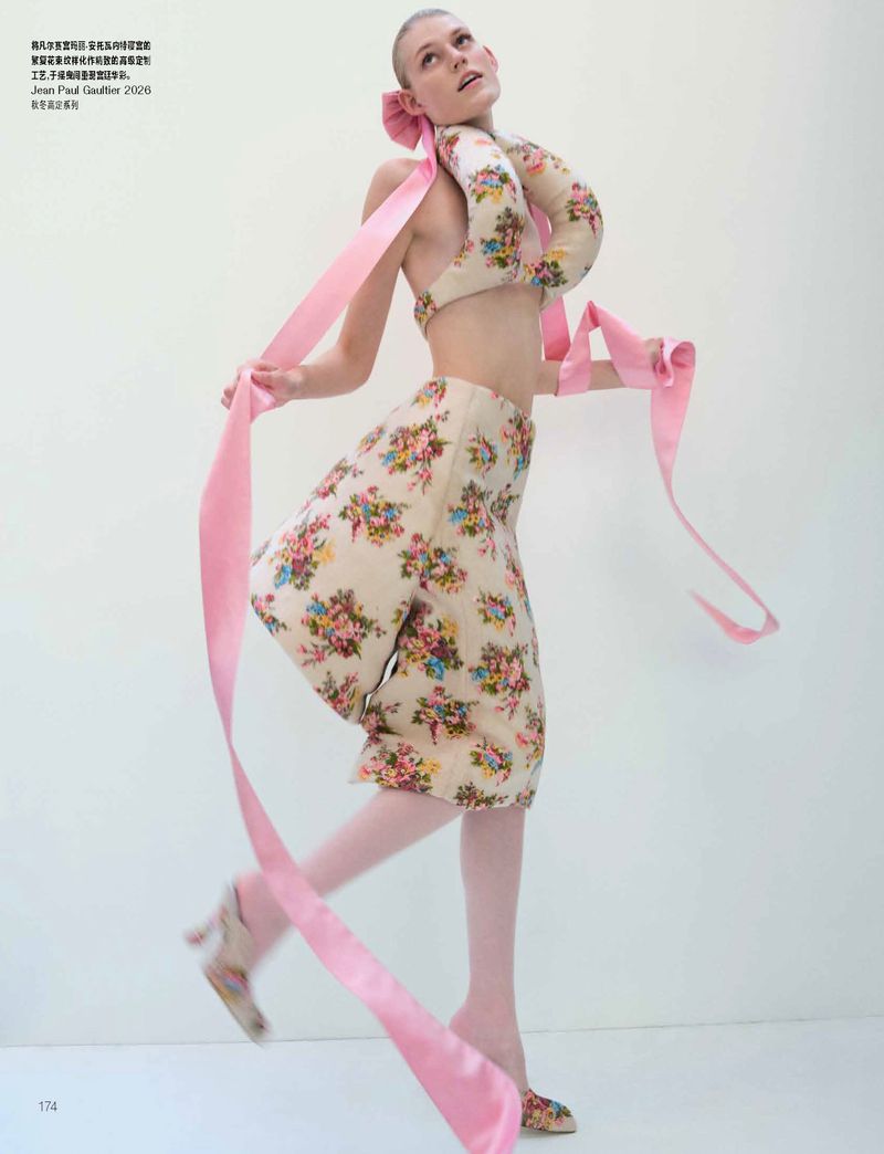 Model in floral two-piece set with long pink ribbons against a seamless white background for Vogue China.