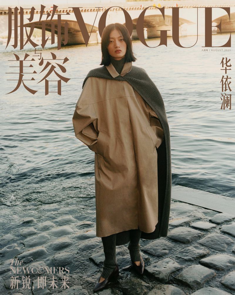 Vogue cover featuring a woman in a trench coat and leggings posing near a river with a bridge in the background.