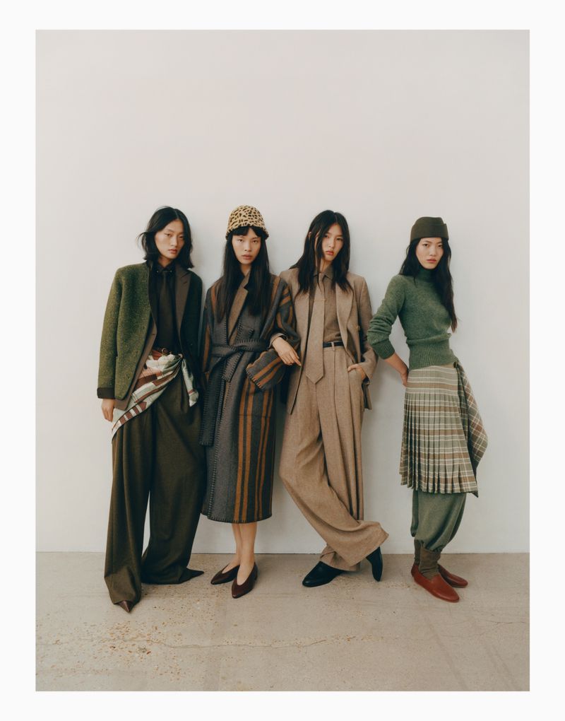 Four young Asian women pose indoors against a white wall, modeling 2024 fall fashion in earthy tones, including suits, separates, and hats.
