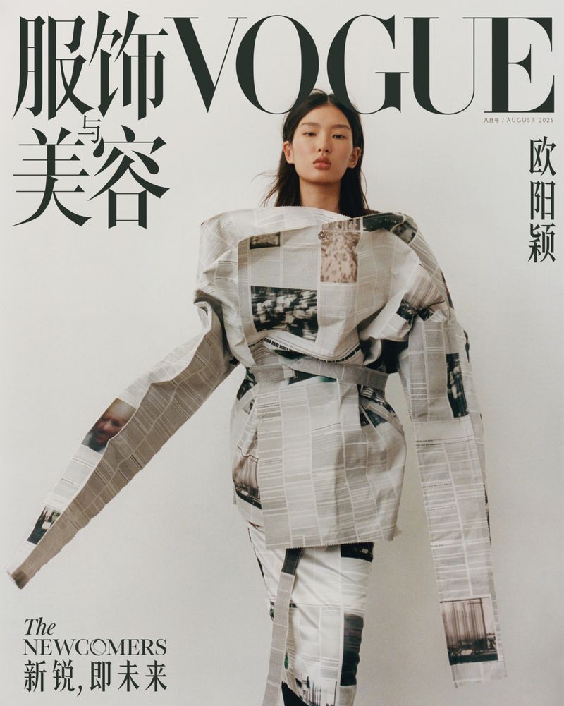 Vogue cover featuring a model wearing a dress made of newspaper, posing in front of a white background with large text on top.