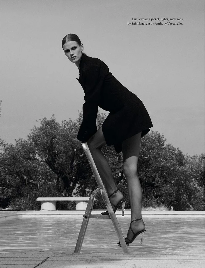 Model Lucia Richardson wearing black jacket and heels on a pool ladder for System Magazine