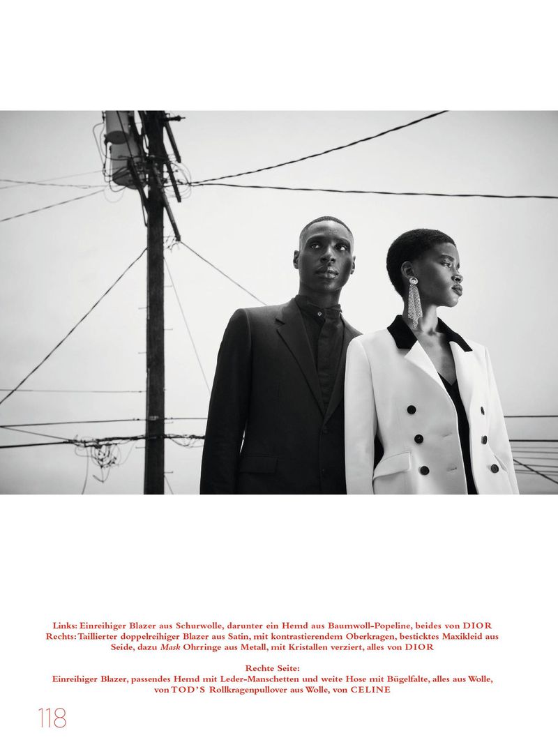 Black and white editorial fashion portrait of two models standing outdoors against a utility pole and power lines