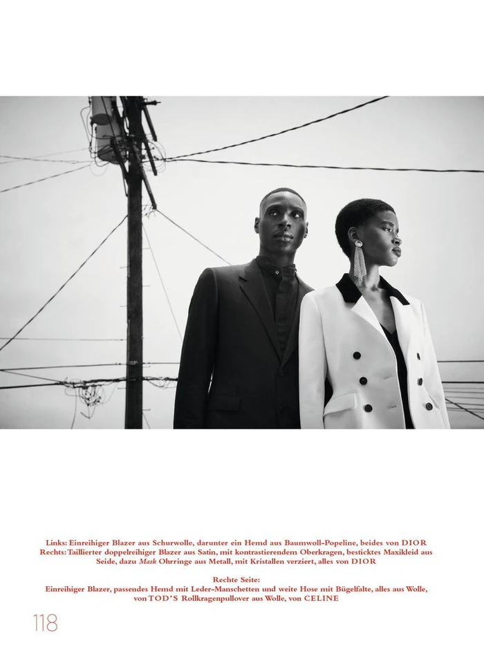 Black and white editorial fashion portrait of two models standing outdoors against a utility pole and power lines