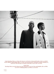 Black and white editorial fashion portrait of two models standing outdoors against a utility pole and power lines