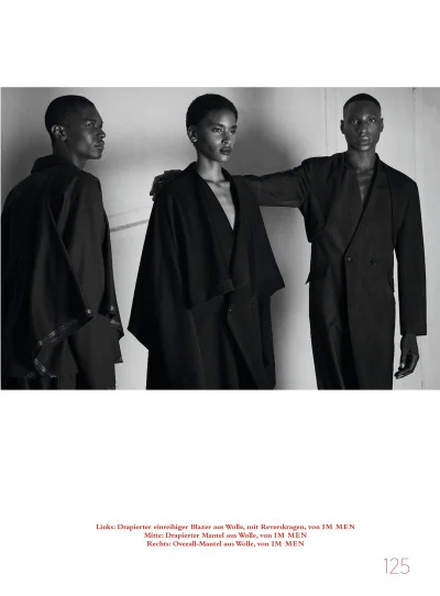 Black and white editorial fashion photograph of three models wearing dark tailored garments against a plain studio background.