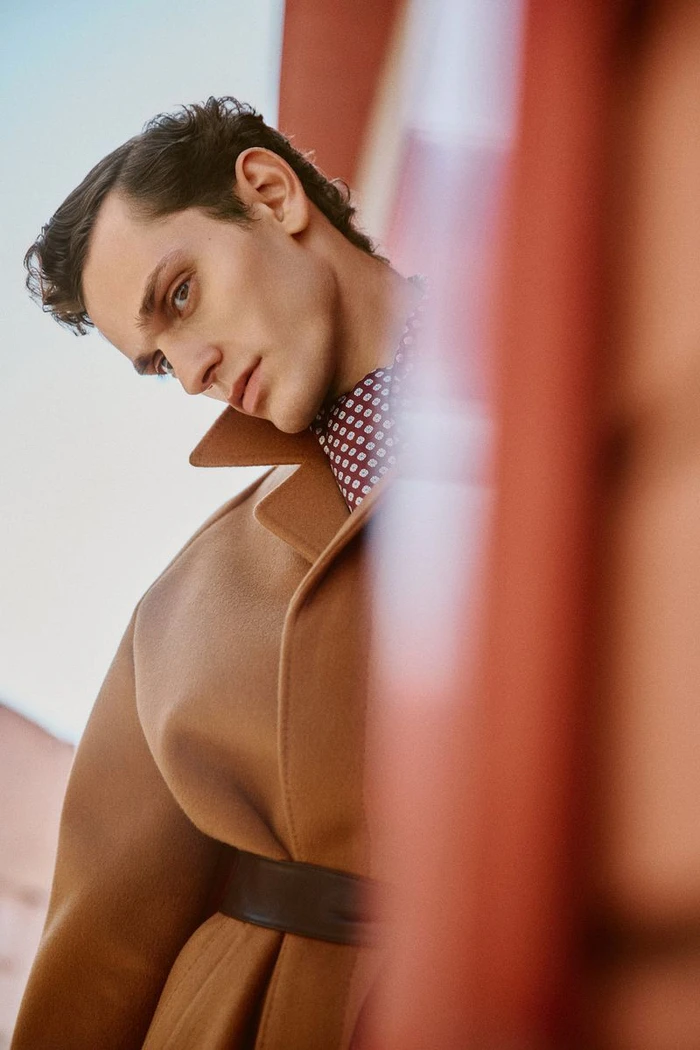 Model wearing a camel coat and patterned shirt posing for Built to Bloom by Esquire Spain photographed by Cristian Hunter.