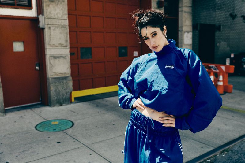 Woman in a blue track suit standing on a city sidewalk in front of a red door for Imagine Magazine shot by Brendan Wixted.