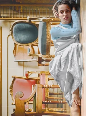 Model wearing a light blue top and white dress leaning against a wall amidst stacked chairs for ICICLE Autumn/Winter 2026 Collection