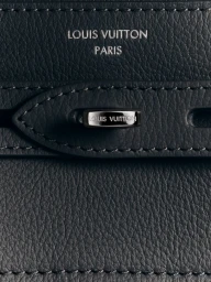 Close-up of black textured leather bag with metallic clasp and debossed Louis Vuitton Paris branding.