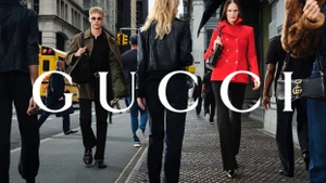 Models walking on a city sidewalk in New York City with a yellow school bus and buildings in the background for Gucci Fall 2026