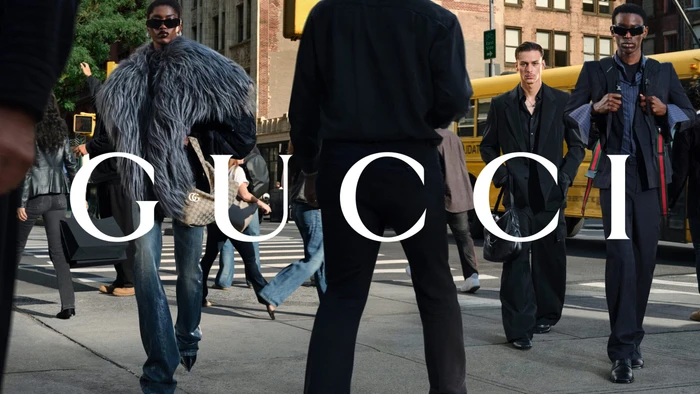 Group of models walking on a New York City street with a yellow bus in the background wearing Gucci