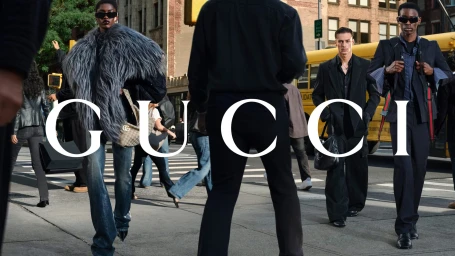 Group of models walking on a New York City street with a yellow bus in the background wearing Gucci