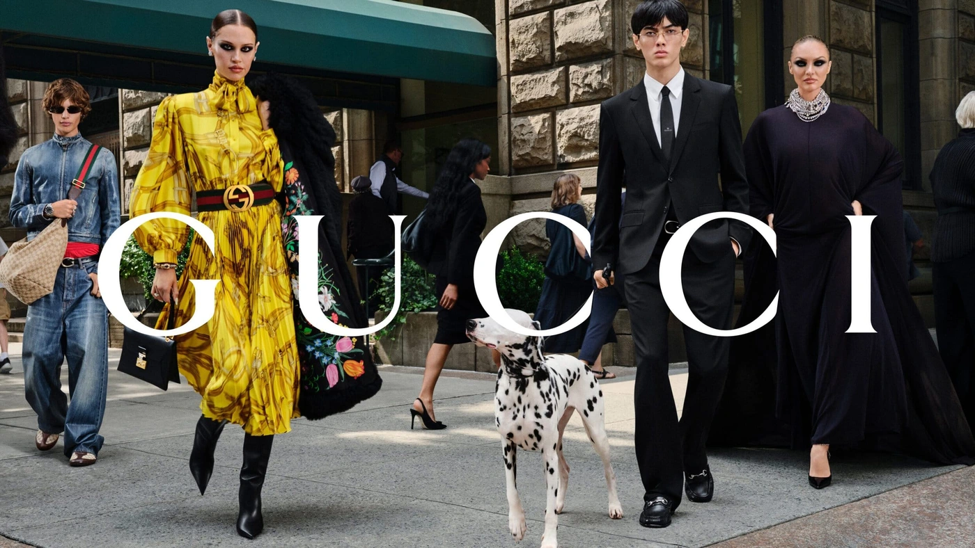 Models and a dalmatian walking on a city sidewalk in a Gucci fall campaign advertisement.