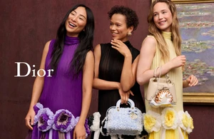 Three female models wearing vibrant dresses against a textured dark wall holding designer handbags for Dior Cruise 2027