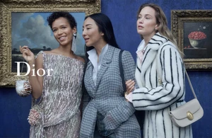 Three models posing in front of framed classical paintings against a textured blue wall for a Dior campaign