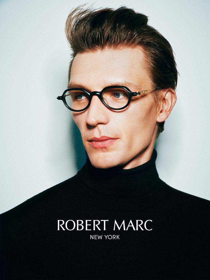 Man wearing dark eyeglasses and a black turtleneck sweater against a light background with overlaid white text.