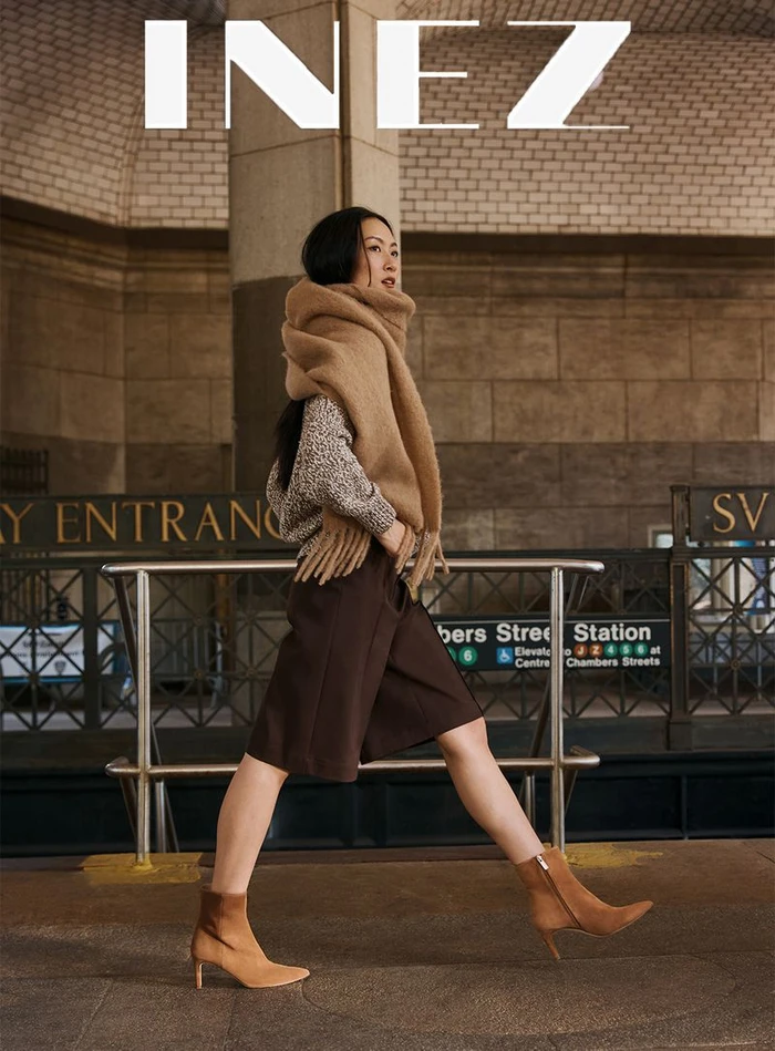 Woman in brown culottes and camel scarf walking through a subway station for Inez Fall 2026