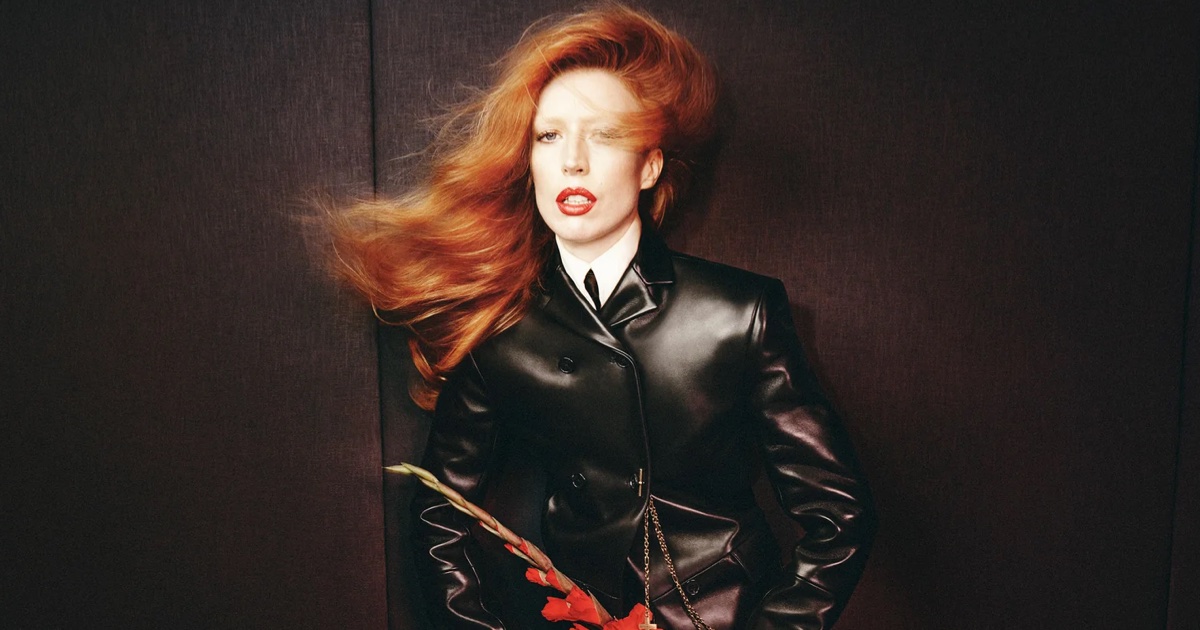 Model Raquel Zimmermann in a black leather jacket with long red hair against a dark textured background for Khaite Fall-Winter 2026 campaign.