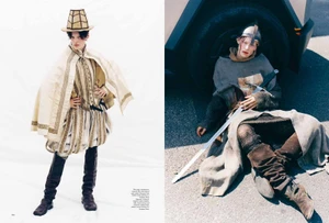 Double page fashion spread featuring two models in historical-inspired medieval attire with armor and weaponry.