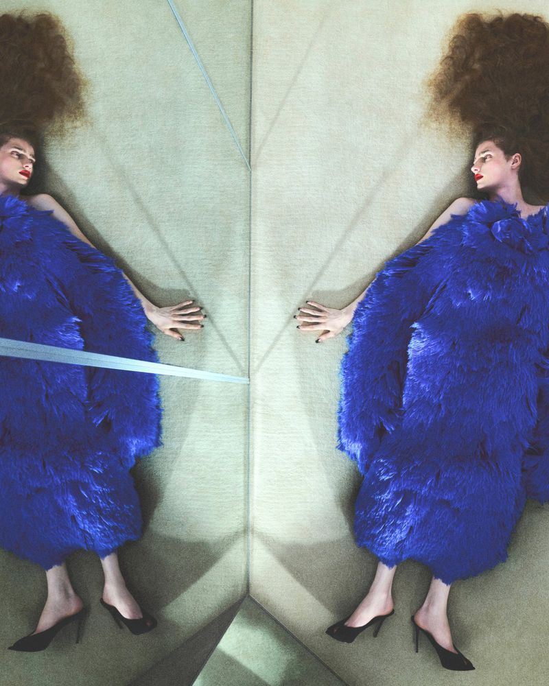 Model in vibrant blue textured dress lying down in a mirrored reflection for Love Magazine shot by Arash Khaksari