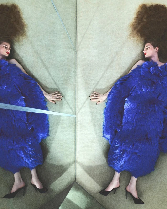 Model in vibrant blue textured dress lying down in a mirrored reflection for Love Magazine shot by Arash Khaksari
