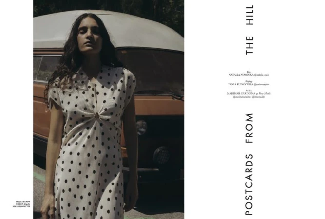 A woman poses in a polka dot dress next to a vintage van outdoors on a sunny day, creating a retro fashion editorial style image.