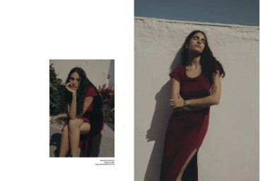 Editorial double-page spread featuring a woman in a dark red dress leaning against a white textured wall outdoors.