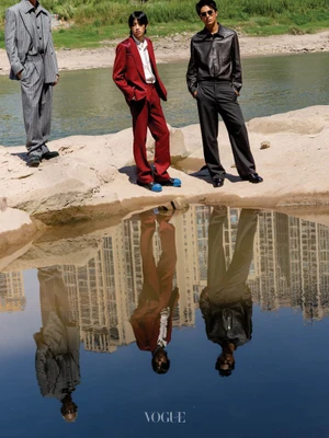 Three male models in tailored suits standing by a calm body of water reflecting city buildings for Vogue China Men