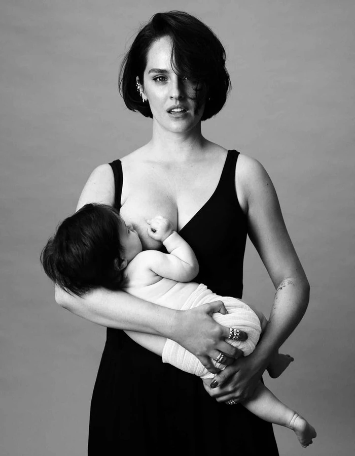 Black and white portrait of actress Noemie Merlant holding and breastfeeding an infant for Madame Figaro
