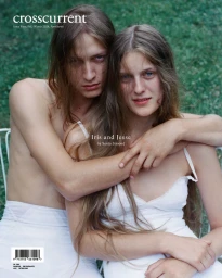 Two people with long brown hair embracing outdoors against a green grass background, wearing white apparel.