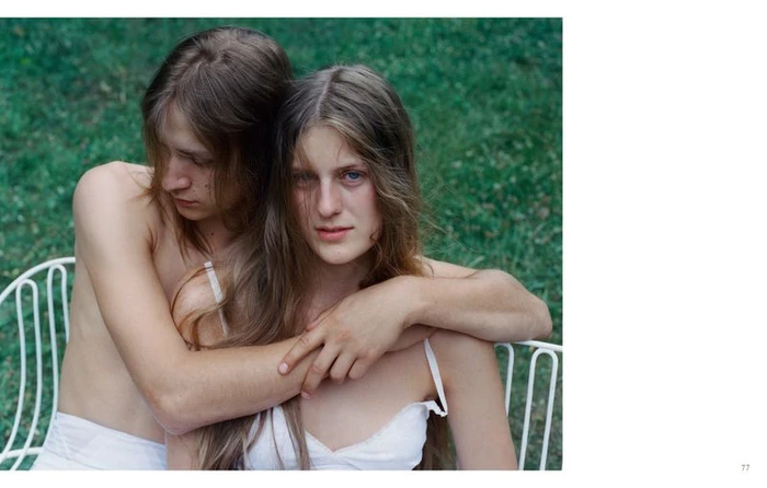 Two young people embracing closely on a white wire garden chair against a green lawn background for Crosscurrent by Senta Simond.