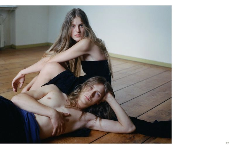 Two models with long hair posing together on a wooden floor in an interior room for Crosscurrent by Senta Simond