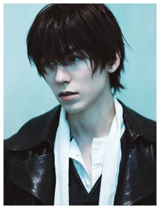 Portrait of Vernon from SEVENTEEN wearing a dark jacket and white scarf against a light blue background