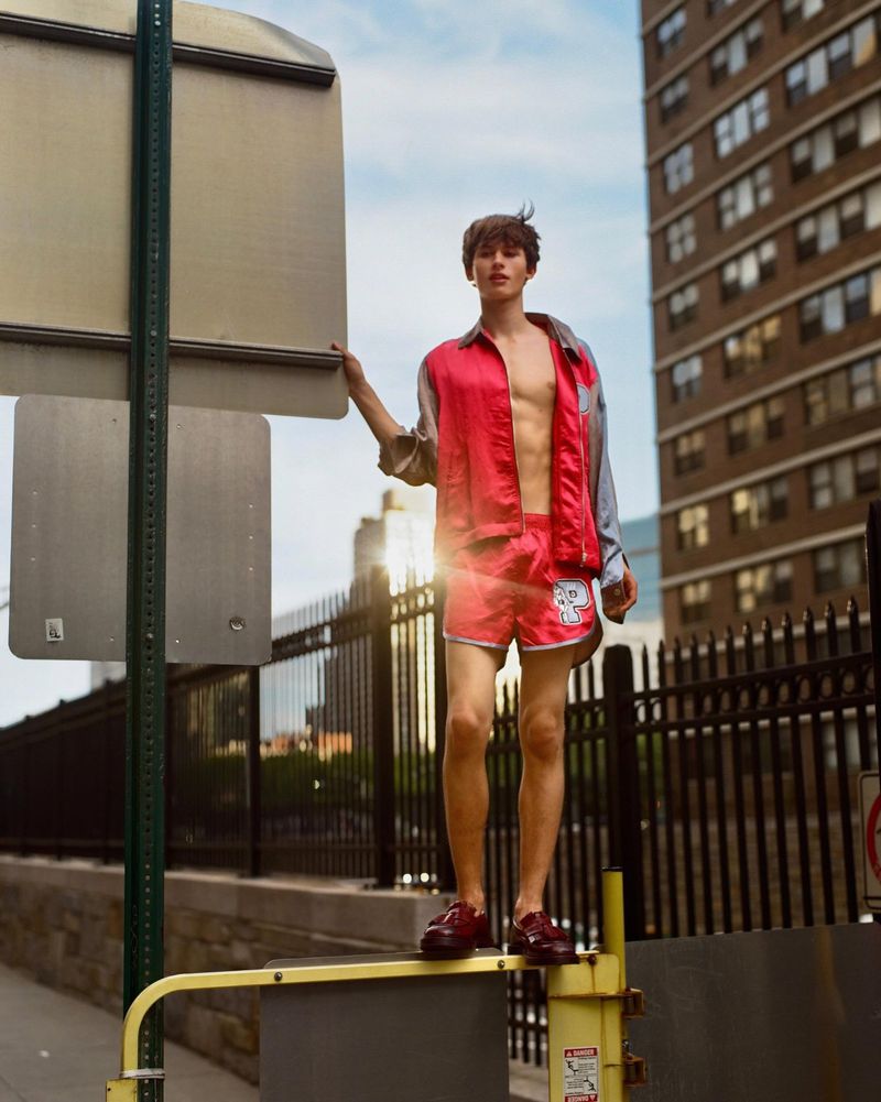 Model Josiah Turner wearing a red satin shirt and shorts standing on a railing for a GQ Turkey editorial by Jasper Soloff.