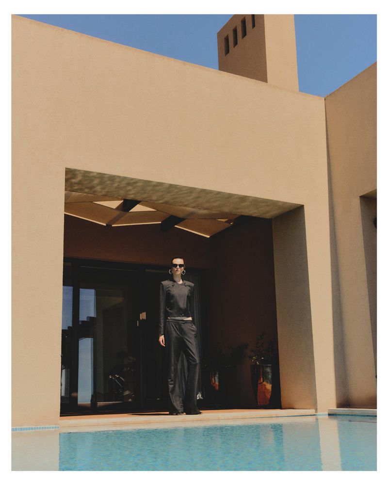 Model Dominika Pikula standing by a swimming pool in front of a modern beige house exterior