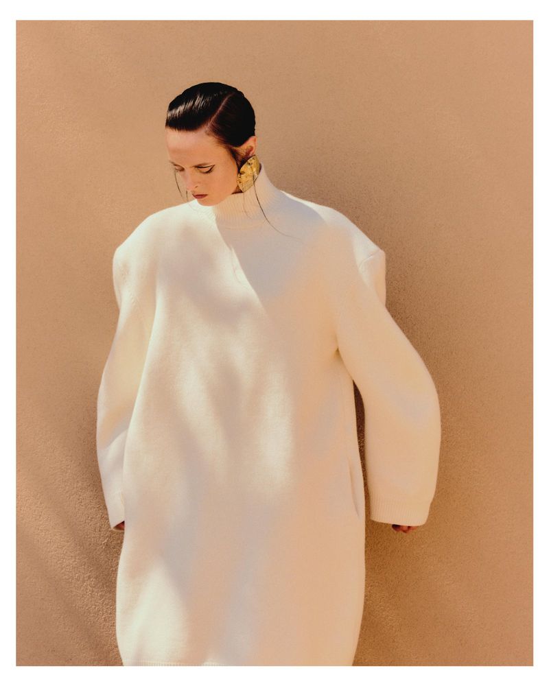 Model Dominika Pikula in an oversized white dress with large gold earrings against a textured warm background for Grazia Germany.