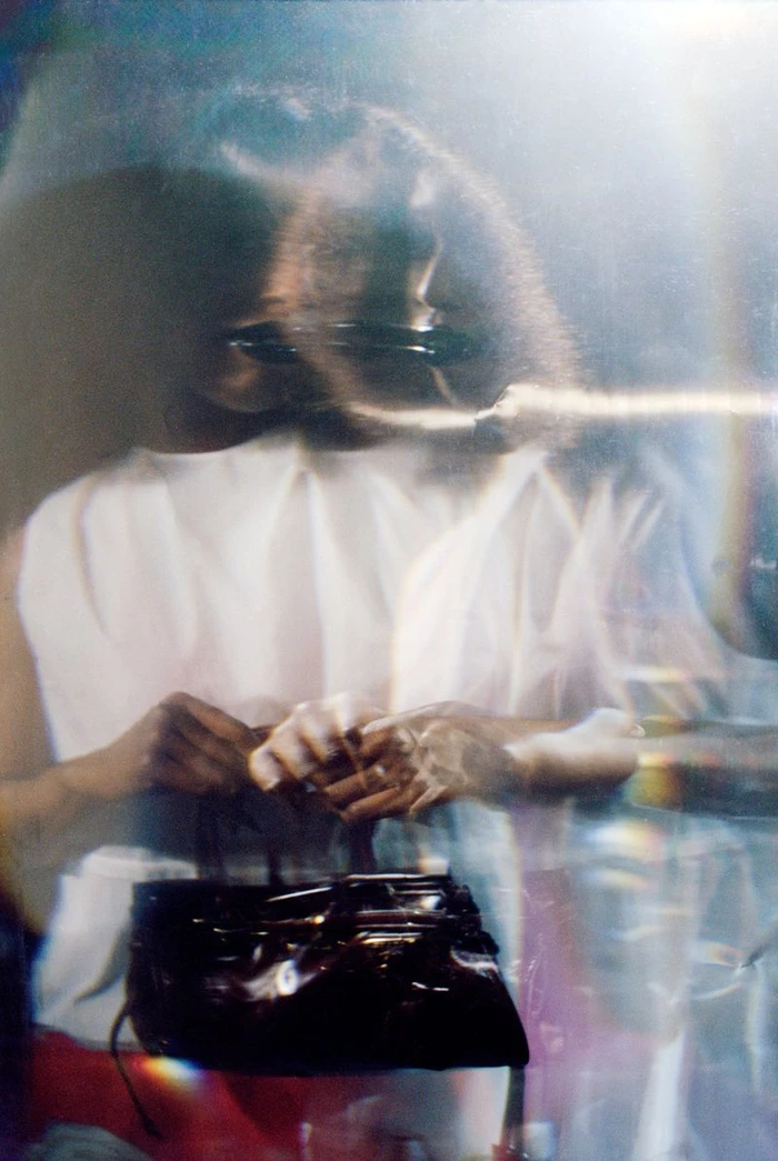 Portrait of John Glacier holding a dark handbag in an i-D Magazine editorial shot with multiple exposures and light streaks.