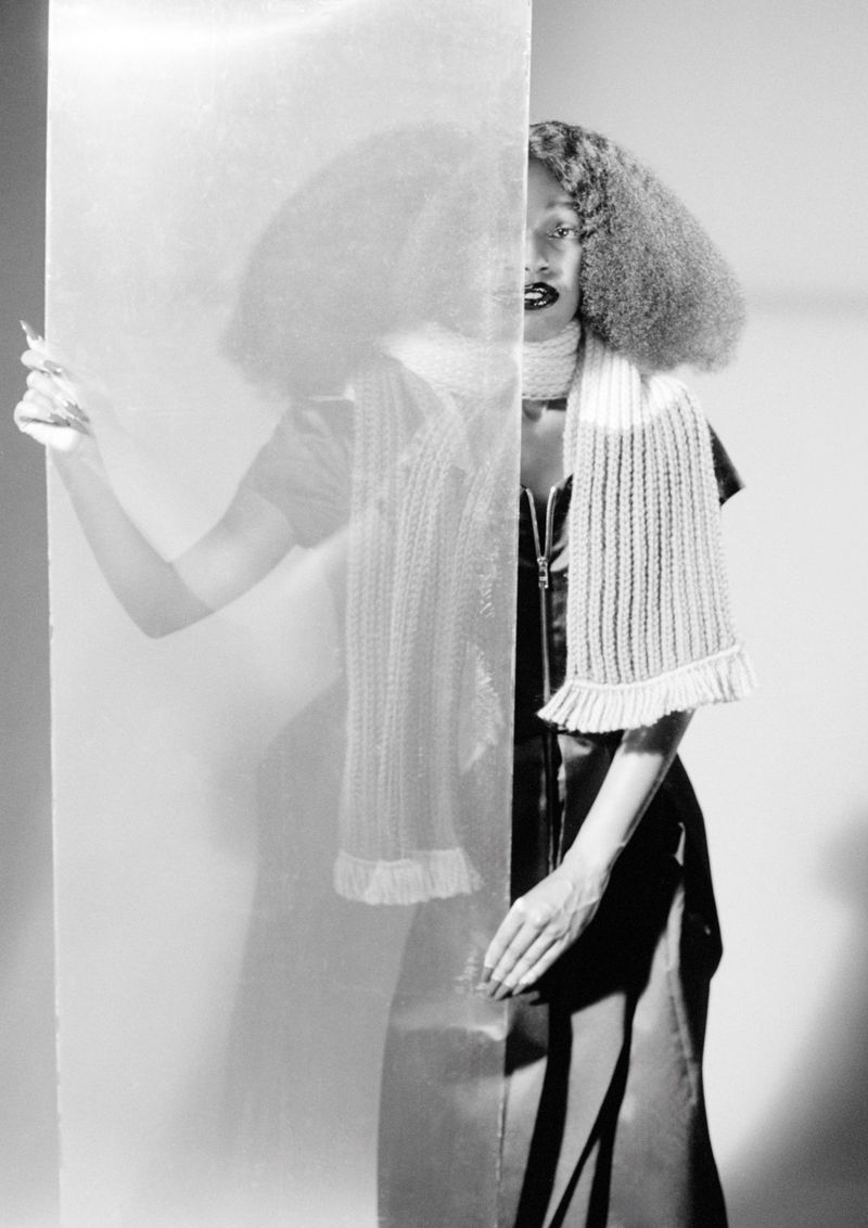Portrait of John Glacier holding a translucent glass panel for i-D Magazine, photographed in monochrome.